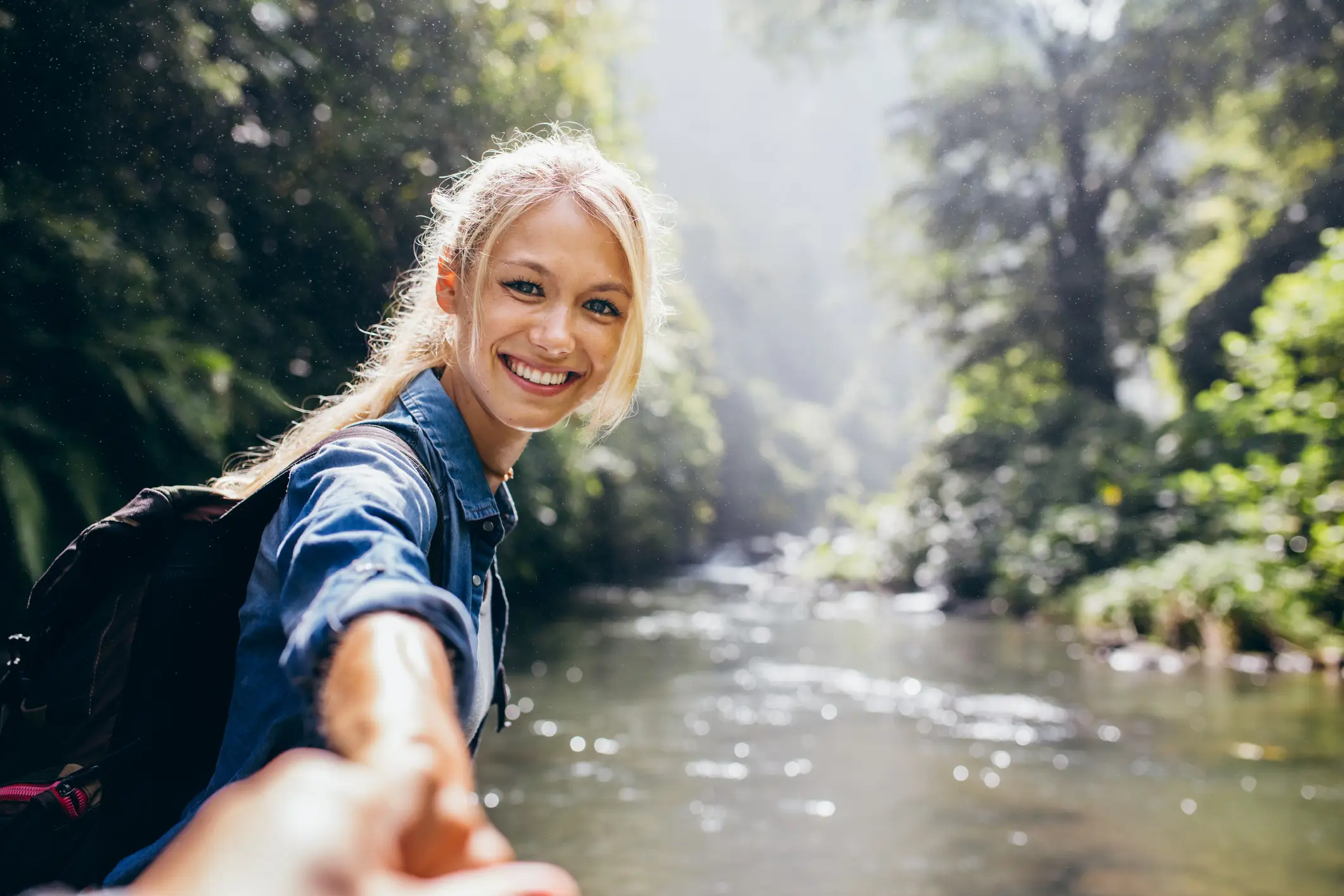 Smiling blond girl reaching her hand to you